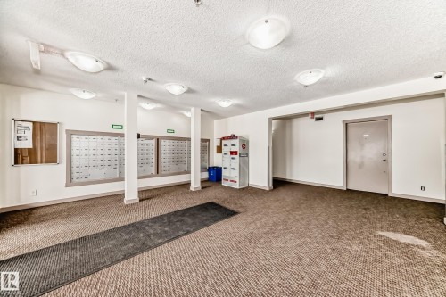 Building entrance featuring textured carpet flooring, recessed lighting, and individual mailboxes - 103 3315 James Mowatt Trail Sw, Edmonton, AB - Indoor Photo Showing Other Room