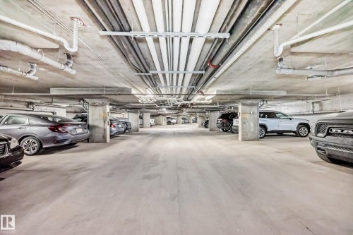 Spacious underground parking garage featuring concrete flooring and structural columns - 103 3315 James Mowatt Trail Sw, Edmonton, AB - Indoor Photo Showing Garage