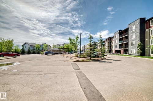 Multi-story building featuring dark stone and red panel siding, with private balconies on each level - 103 3315 James Mowatt Trail Sw, Edmonton, AB - Outdoor