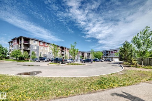 Multi-story residential building featuring balconies, a stone facade, and red and beige siding - 103 3315 James Mowatt Trail Sw, Edmonton, AB - Outdoor
