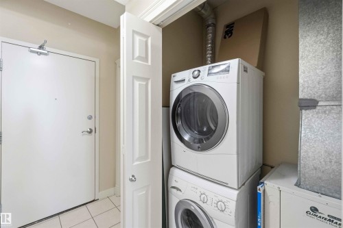 Dedicated laundry area featuring stacked front-load washer and dryer units - #708 9939 109 St Nw, Edmonton, AB - Indoor Photo Showing Laundry Room