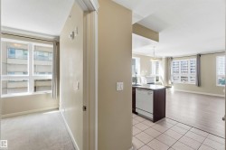 Open-concept living space featuring a kitchen island with integrated dishwasher, tile flooring, and light wood-finish flooring - 