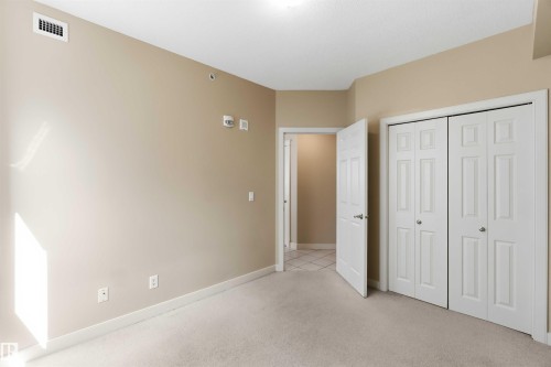 Neutral-toned carpeting complements the light beige wall finish - #708 9939 109 St Nw, Edmonton, AB - Indoor