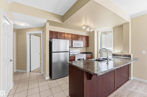 Kitchen featuring a central island with an integrated double sink and a gooseneck faucet - #708 9939 109 St Nw, Edmonton, AB - Indoor Photo Showing Kitchen With Double Sink