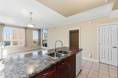 Kitchen island with dual stainless steel sinks and a chrome faucet - #708 9939 109 St Nw, Edmonton, AB - Indoor Photo Showing Kitchen With Double Sink