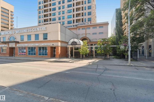 Commercial building with an arched entry canopy, a prominent street-facing facade, and multiple large storefront windows - #708 9939 109 St Nw, Edmonton, AB - Outdoor With Facade