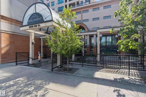 Building exterior featuring a domed glass entryway, prominent signage, and a paved sidewalk - #708 9939 109 St Nw, Edmonton, AB - Outdoor
