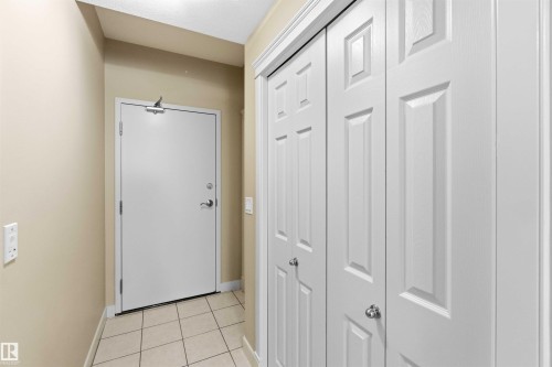 Entryway featuring square floor tiles, a white paneled closet, and a light beige wall finish - #708 9939 109 St Nw, Edmonton, AB - Indoor Photo Showing Other Room