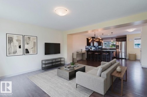 Open-concept living area featuring dark wood-finish flooring, recessed lighting, and a neutral color palette - 6717 Elston Lane Nw, Edmonton, AB - Indoor Photo Showing Living Room