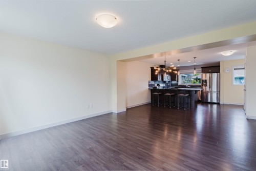 Open-concept living space featuring wood-finish flooring, recessed lighting, and a kitchen with dark cabinetry - 6717 Elston Lane Nw, Edmonton, AB - Indoor Photo Showing Living Room