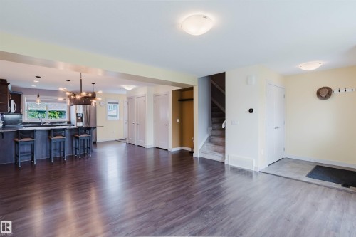 Open concept living space featuring wood-finish flooring, a kitchen island with seating, dark wood cabinetry, and stainless steel appliances - 6717 Elston Lane Nw, Edmonton, AB - Indoor Photo Showing Other Room