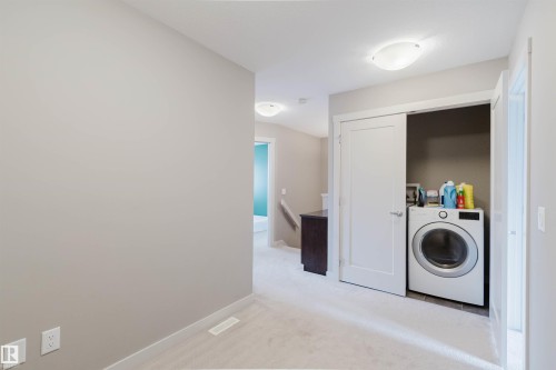 Upper-level laundry closet featuring a front-loading appliance and bi-fold door - 6717 Elston Lane Nw, Edmonton, AB - Indoor Photo Showing Laundry Room