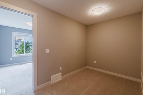 Compact room featuring neutral-toned walls, contrasting white baseboards, and a flush-mount ceiling light - 6717 Elston Lane Nw, Edmonton, AB - Indoor Photo Showing Other Room