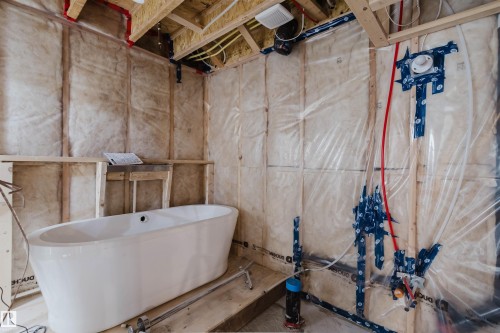 Freestanding white bathtub on a partially finished floor, surrounded by insulated walls with visible studs and plumbing - 6717 Elston Lane Nw, Edmonton, AB - Indoor Photo Showing Basement