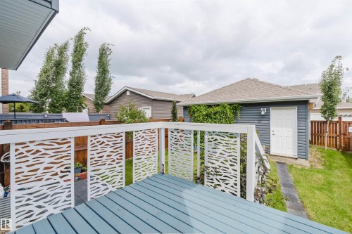 Outdoor deck featuring decorative white railings, composite decking, and a backyard with a detached garage - 6717 Elston Lane Nw, Edmonton, AB - Outdoor