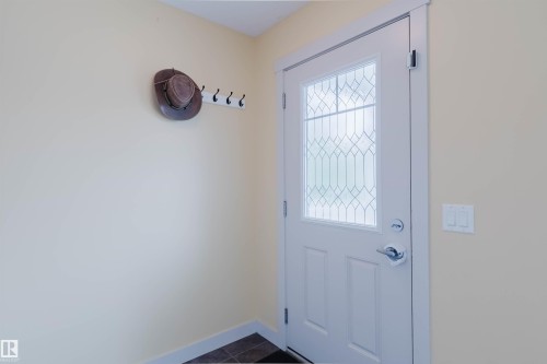 Entryway featuring a white door with decorative glass, bright interior walls, white trim, and dark floor tiles - 6717 Elston Lane Nw, Edmonton, AB - Indoor Photo Showing Other Room