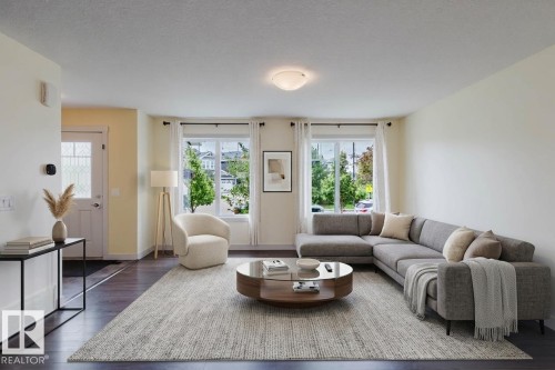 Spacious living area featuring wood-finish flooring, abundant natural light from multiple windows, and a recessed ceiling light fixture - 6717 Elston Lane Nw, Edmonton, AB - Indoor Photo Showing Living Room