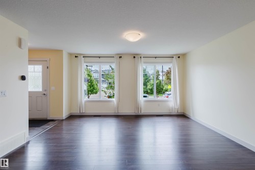 Spacious room featuring rich wood-finish flooring, bright white walls, and a recessed ceiling light - 6717 Elston Lane Nw, Edmonton, AB - Indoor
