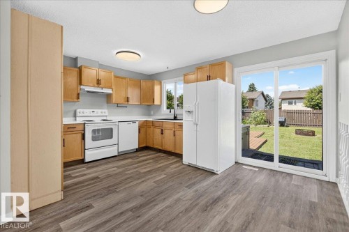 Kitchen featuring wood cabinetry, white appliances, light countertops, and wood-finish flooring - 4212 32 Avenue Nw, Edmonton, AB - Indoor Photo Showing Kitchen