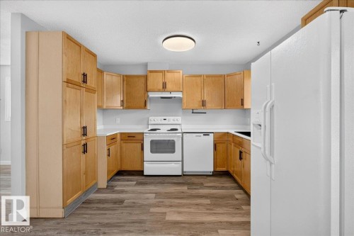 U-shaped kitchen featuring wood cabinetry with dark hardware, white countertops, and wood-finish flooring - 4212 32 Avenue Nw, Edmonton, AB - Indoor Photo Showing Kitchen