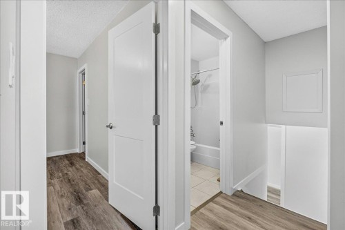 Hallway featuring wood-finish flooring, light gray walls, white trim, and a contemporary white panel door - 4212 32 Avenue Nw, Edmonton, AB - Indoor Photo Showing Other Room