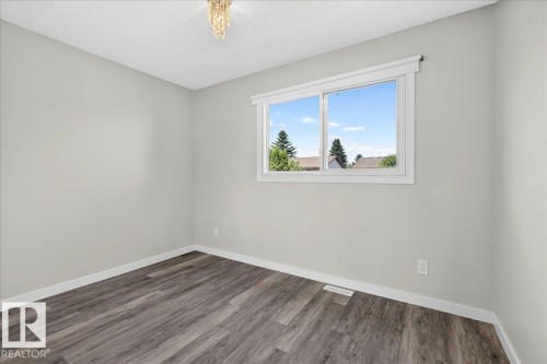 Room featuring light gray walls, wood-finish flooring, a white trim window, and a ceiling-mounted light fixture - 4212 32 Avenue Nw, Edmonton, AB - Indoor Photo Showing Other Room