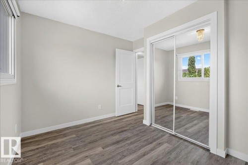 Bedroom featuring wood-finish flooring, light neutral wall paint, white baseboards, and a white ceiling - 4212 32 Avenue Nw, Edmonton, AB - Indoor Photo Showing Other Room