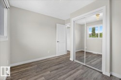 Bedroom featuring wood-finish flooring, light neutral wall paint, white baseboards, and a white ceiling - 