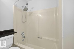 Tub and shower combination featuring a multi-function showerhead with a handheld sprayer, chrome fixtures, and a light-colored tub surround - 