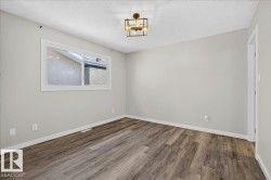 Room featuring wood-finish flooring, light gray wall paint, and white baseboards - 