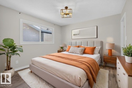Bedroom featuring light wood-finish flooring, a white trim window, and a contemporary ceiling light fixture - 4212 32 Avenue Nw, Edmonton, AB - Indoor Photo Showing Bedroom
