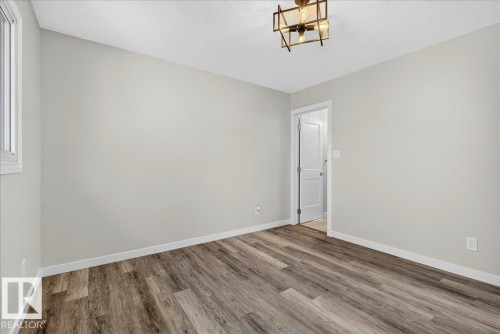 Room featuring wood-finish flooring, a white window frame, contemporary light fixture, and neutral wall tones - 4212 32 Avenue Nw, Edmonton, AB - Indoor Photo Showing Other Room