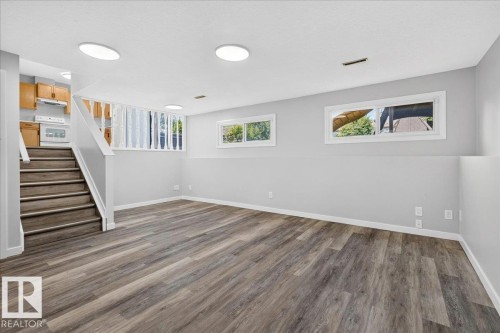 Lower-level living area featuring wood-finish flooring, recessed lighting, and multiple windows - 4212 32 Avenue Nw, Edmonton, AB - Indoor Photo Showing Other Room