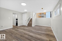 Spacious room with wood-finish flooring, light grey walls, and recessed ceiling lighting - 