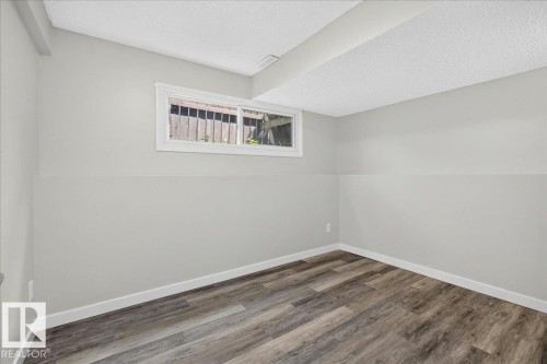 Room featuring wood-finish flooring, light grey walls, white trim, and a white-framed window - 4212 32 Avenue Nw, Edmonton, AB - Indoor Photo Showing Other Room