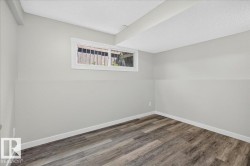 Room featuring wood-finish flooring, light grey walls, white trim, and a white-framed window - 
