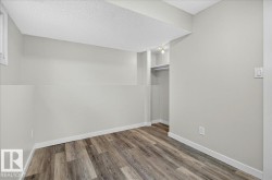 Room featuring wood-finish flooring, light gray walls, white trim, and a built-in closet with shelving and a hanging rod - 