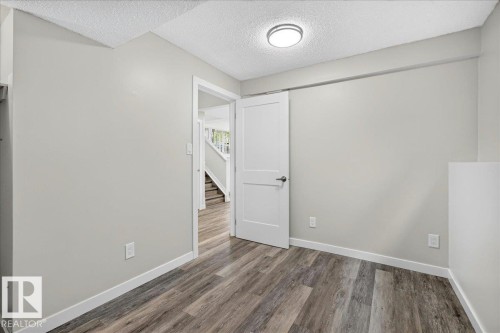 Interior room featuring wood-finish flooring, light gray walls, and white trim - 4212 32 Avenue Nw, Edmonton, AB - Indoor Photo Showing Other Room