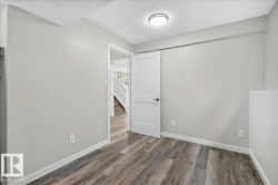 Interior room featuring wood-finish flooring, light gray walls, and white trim - 