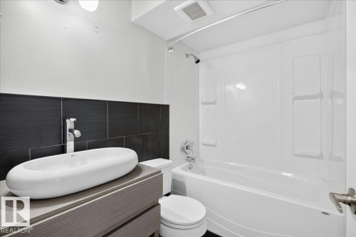 Bathroom featuring a modern vessel sink, chrome faucet, and wood-finish vanity - 4212 32 Avenue Nw, Edmonton, AB - Indoor Photo Showing Bathroom