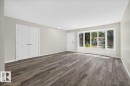 Spacious living area featuring wood-finish flooring, a large bay window, fresh neutral paint, white trim, and a flush-mount ceiling light - 4212 32 Avenue Nw, Edmonton, AB  - Indoor Photo Showing Other Room 