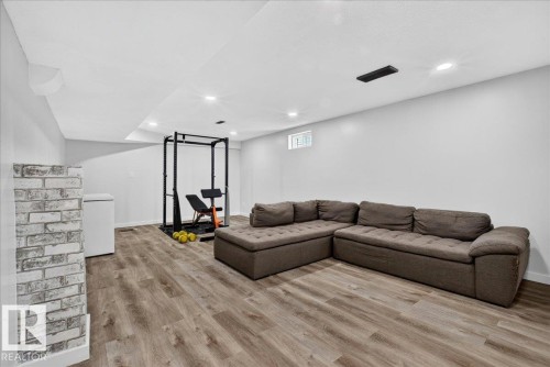 Spacious lower-level room featuring wood-finish flooring, white painted walls, and recessed ceiling lighting - 4212 32 Avenue Nw, Edmonton, AB - Indoor
