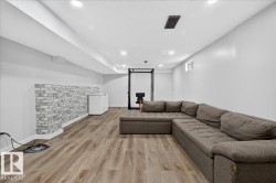 Finished lower level featuring recessed lighting, durable wood-finish flooring, and a decorative faux brick accent wall - 