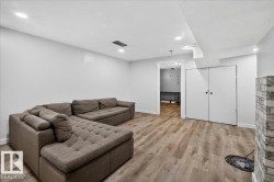 Spacious interior room featuring wood-finish flooring, recessed ceiling lighting, and a white brick-style column - 
