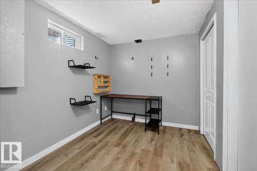 Interior space featuring wood-finish flooring, light grey walls, and a white bi-fold door - 4212 32 Avenue Nw, Edmonton, AB - Indoor Photo Showing Other Room
