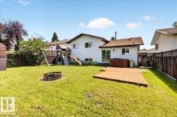 Expansive backyard featuring a lush lawn, a fire pit, and a wooden deck - 