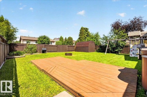 Spacious backyard featuring a large wooden deck, manicured lawn, full privacy fencing, and a storage shed - 4212 32 Avenue Nw, Edmonton, AB - Outdoor With Deck Patio Veranda With Backyard
