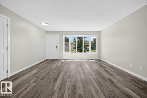 Spacious interior room featuring wood-finish flooring, light gray wall paint, and white baseboards - 4212 32 Avenue Nw, Edmonton, AB - Indoor