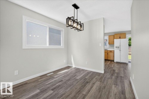 Versatile interior space featuring wood-finish flooring and a contemporary linear chandelier - 4212 32 Avenue Nw, Edmonton, AB - Indoor Photo Showing Other Room