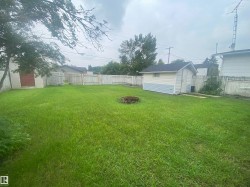 Expansive backyard featuring a lush lawn, two storage sheds, and full perimeter fencing - 